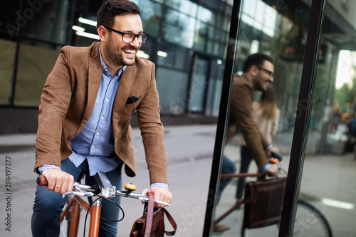 Cuadros en Lienzo Happy young stylish businessman going to work by bike
