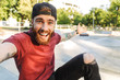 © Drobot Dean - Attractive cheerful young man sitting at the skate park ramp
