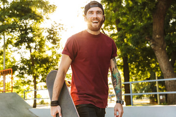 Happy cheerful young man walking at the skate park ramp