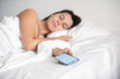 © phpetrunina14 - woman sleeping in bed phone in her hand