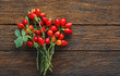 rosehip branches with red dog rose fruits on a brown wooden table