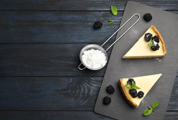 Pieces of delicious cheesecake with blackberries on dark wooden background, flat lay. Space for text