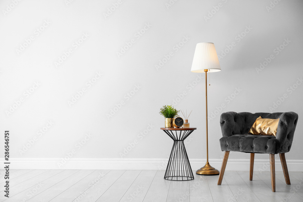 Stylish room interior with comfortable armchair, floor lamp near light wall, space for text - obrazy, fototapety, plakaty 