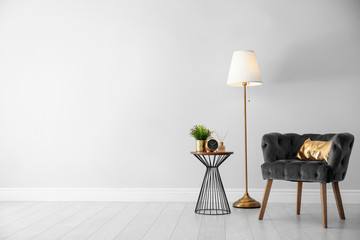 Poster - stylish room interior with comfortable armchair, floor lamp near light wall, space for text