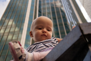 One year old girl on the background of a skyscraper. Travel with children, the development of emotional intelligence. Early development.