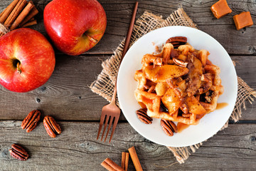 Poster - Sweet breakfast waffle with baked apple, pecans and caramel. Above view table scene over a rustic wood background. Autumn food theme.