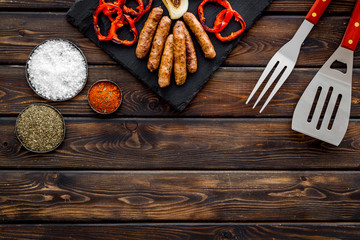 Grilled sausages, vegetables on kitchen board and spices on wooden background top view mockup