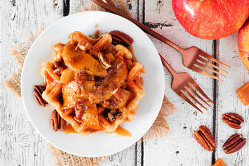 Poster - Sweet breakfast waffle with baked apple, pecans and caramel. Top view over a white wood background. Autumn food theme.