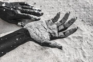 Wall Mural - close up of woman hands painted black on sand. conceptual image