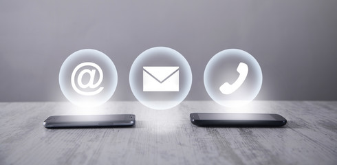 Wall Mural - smartphones with contact symbols in the desk.