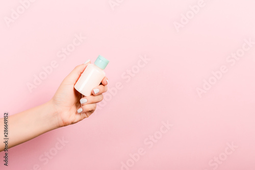 Photographie Female hand holding cream bottle of lotion isolated