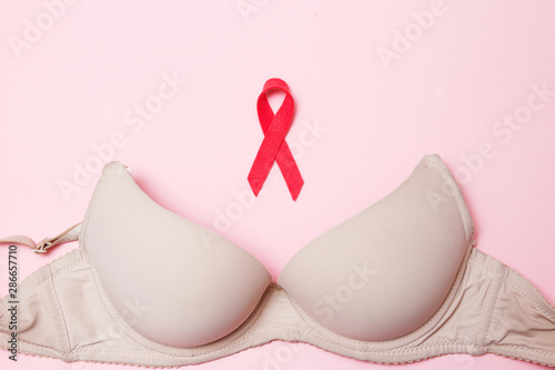 Bra with a symbol of the month of breast cancer awareness on a pink background top view, flat lay. Women\'s Health Concept.