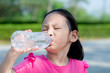 © nuiiko - Happy Asian girl drinking a bottle of water outdoor.