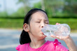 © nuiiko - Happy Asian girl drinking a bottle of water outdoor.