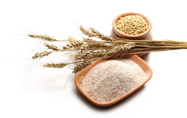 Wheat grains, ears, and integral flour in clay pot isolated on white background 