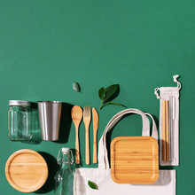 Sustainable Lifestyle. Zero Waste, Plastic Free Shopping Concept. Cotton Bags, Glass Jar, Bottle, Metal Cup, Straws For Drinking, Bamboo Cutlery And Boxes On Green Background.