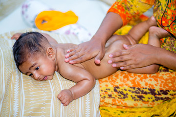 Wall Mural - A mom massaging a six month age baby boys soft body.