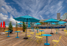 Yellow Chairs With Teal Umbrellas And Tables On Wood Deck