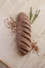 composition of dark bread with scattered buckwheat and sprigs of rosemary on baking canvas