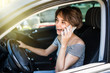 Young pretty woman with telephone having phone conversation while driving car