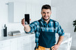 © LIGHTFIELD STUDIOS - selective focus of happy bearded handyman holding smartphone with blank screen