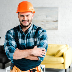 Wall Mural - cheerful handyman looking at camera while standing with crossed arms