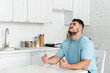 © LIGHTFIELD STUDIOS - angry man gesturing while sitting near table in kitchen