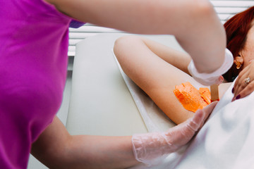 Close up of woman getting waxing armpit b y beautician in a beauty salon.