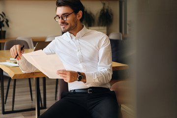 Aufkleber - Young handsome businessman in eyeglasses happily working with papers in office