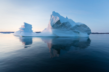 photogenic and intricate iceberg under an interesting and blue sky during sunset. effect of global w