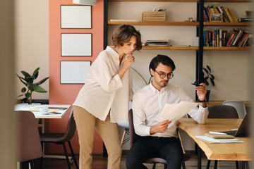 Aufkleber - Two young business colleagues thoughtfully working with papers in office