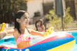 © FotoAndalucia - six-year-old girl plays with boat-shaped inflatable mat and her mother smiles in the background in swimming pool
