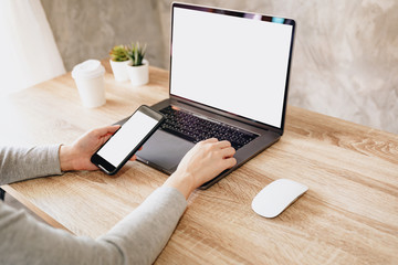 Wall Mural - Asian woman holding phone and using computer laptop on wooden table