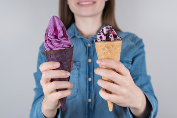 Cropped closeup photo of delightful satisfied dreamy lovely girl holding two colorful ice creams in hands isolated grey background