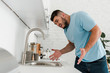 © LIGHTFIELD STUDIOS - selective focus of upset man gesturing while looking at sink in modern kitchen