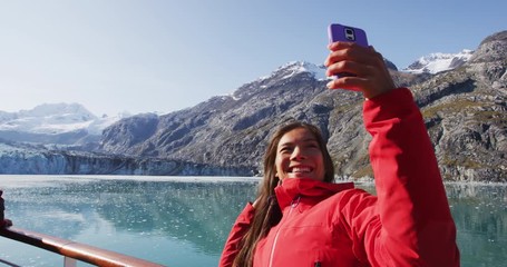 Wall Mural - Cruise ship passenger taking selfie photo in Glacier Bay National Park, Alaska, USA. Woman on travel sailing Inside Passage enjoying view of Johns Hopkins Glacier.