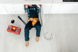 © LIGHTFIELD STUDIOS - top view of handyman lying on floor near toolbox