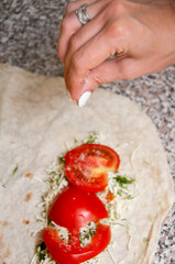 Wall Mural - Cooking suluguni in pita bread with tomato and herbs. Pita bread with herbs and cheese with tomato on a gray table.