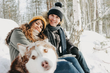 The happy couple with dog haski at forest nature park in cold season. Travel adventure love story