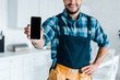 © LIGHTFIELD STUDIOS - cropped view of happy bearded handyman holding smartphone with blank screen