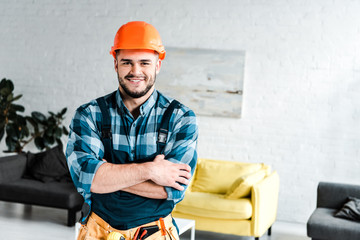 Wall Mural - happy handyman looking at camera while standing with crossed arms