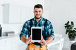 © LIGHTFIELD STUDIOS - happy handyman holding digital tablet with blank screen