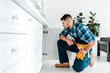 © LIGHTFIELD STUDIOS - selective focus of handsome handyman with tool belt sitting near kitchen cabinet