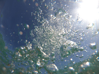 Underwater bubbles with sunlight through water surface as seen in natural scene at Caribbean turquoise open ocean sea