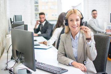 Wall Mural - Portrait of smiling female customer service representative with colleagues working in office