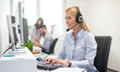 © Bojan - Young blond woman with headset working on computer in office