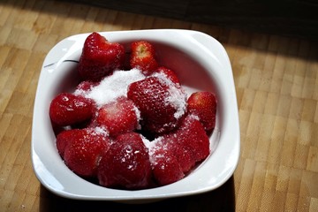 juicy fres strawberries in the bowl covered with white sugar