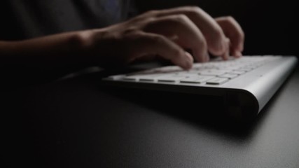 Close-up man typing on computer keyboard with hands and fingers. Macro soft focus dolly shot. Computer programming, text chat online messaging and online marketing business concept.
