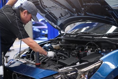 Fotomural Asian male auto mechanic examine car engine breakdown problem in front of automotive vehicle car hood