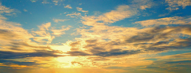 beautiful sunset in the sky with sky blue and orange light of the sun through the dark clouds in the